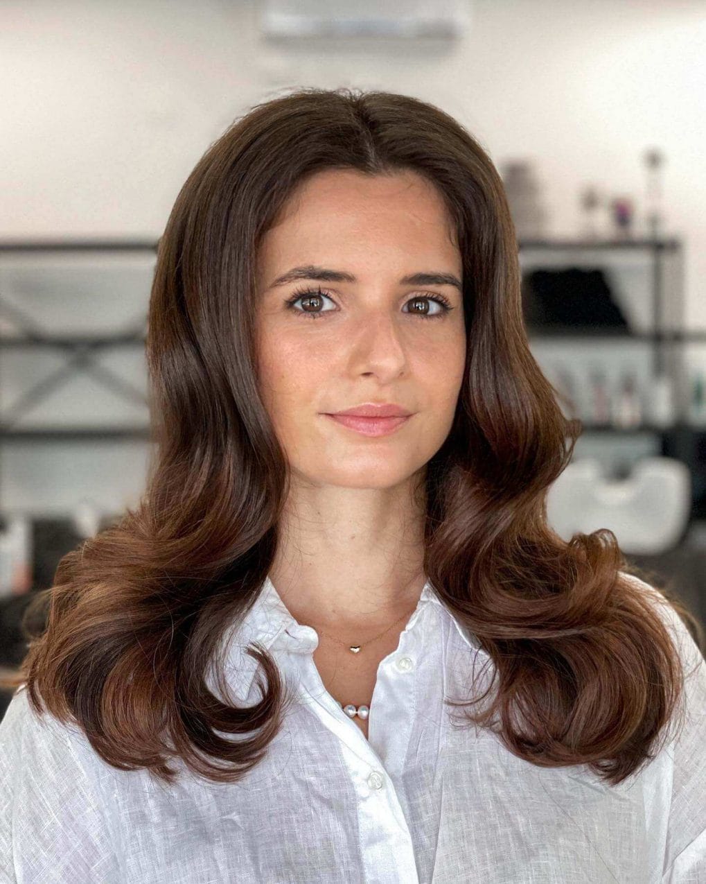 Classic '90s voluminous brunette with auburn highlights, curled blowout ends.