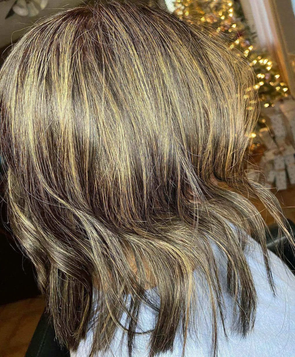 Medium-length cut with soft inward curls and warm highlights.