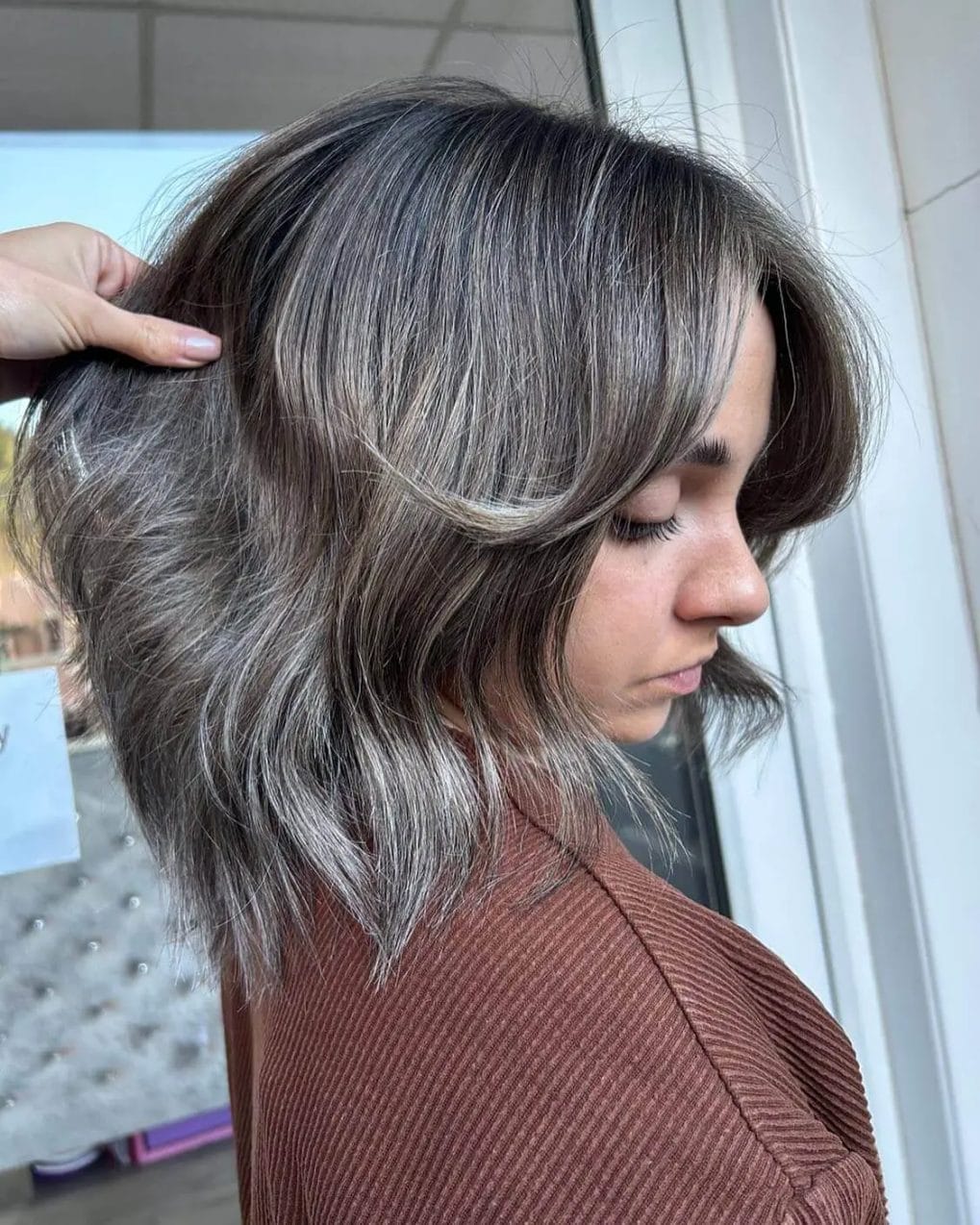 Contemporary ash balayage bob with softly curtained bangs, embodying winter chic.