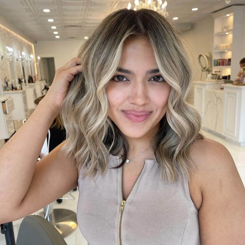Ashy blonde balayage with soft waves at shoulder-length.