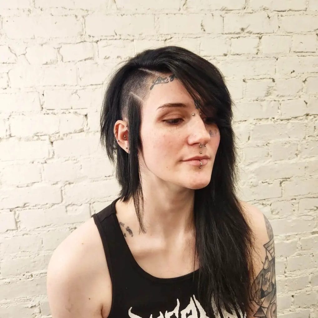 Asymmetric undercut with a long, side-swept jet black fringe and artistically carved geometric patterns.
