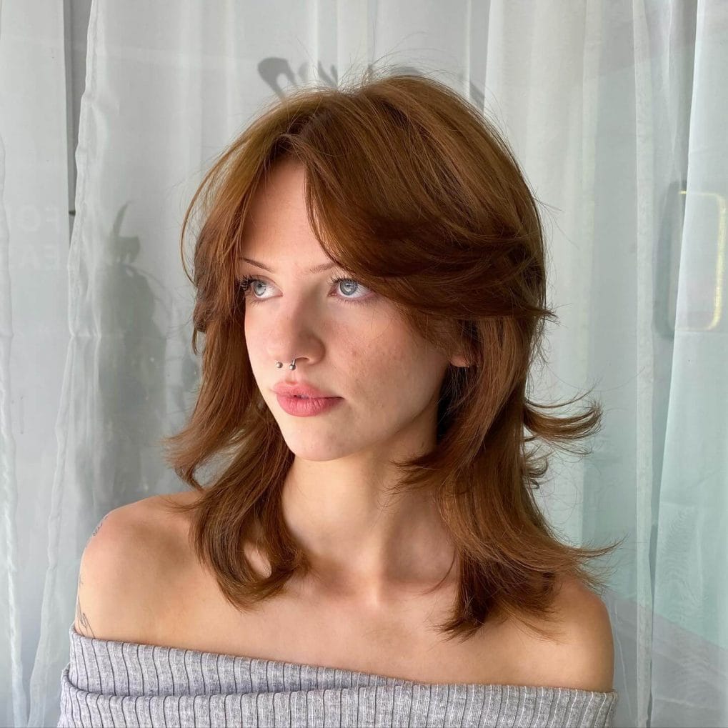 Flowing medium auburn layers with middle-parted curtain bangs and slight outward flick at ends.