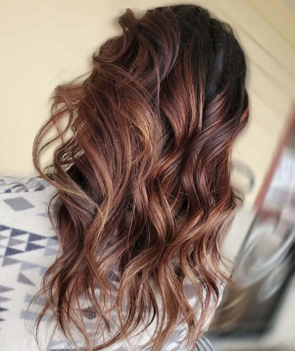 Deep auburn and mahogany balayage with cascading waves, evoking winter warmth.