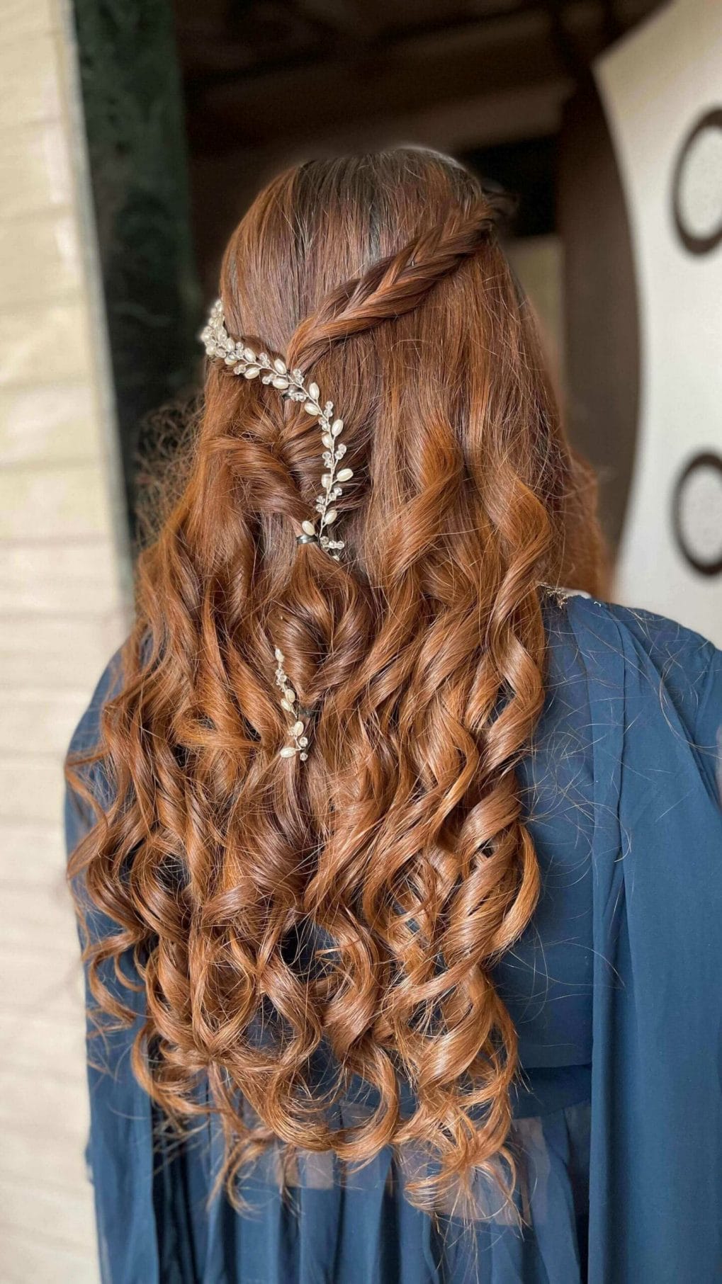 Side braid in auburn curls met with a sparkling accessory
