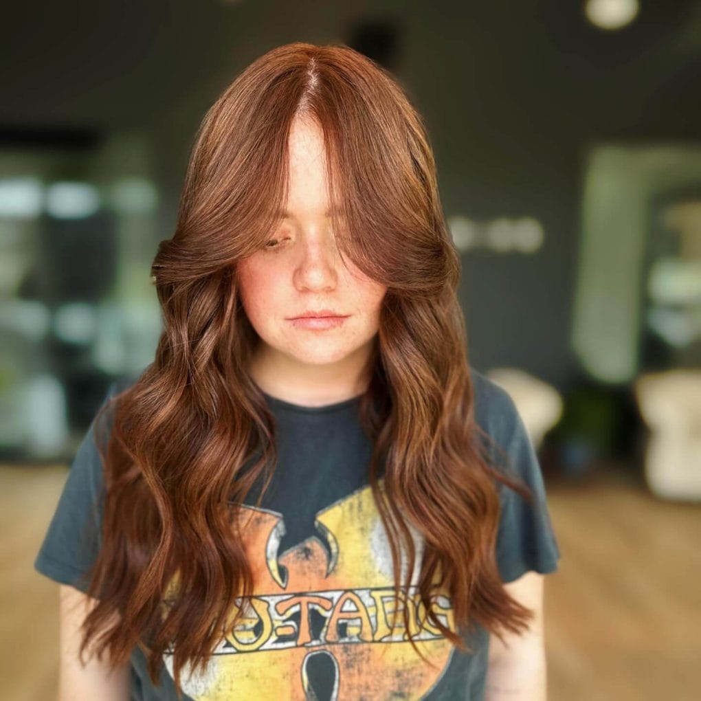 Long wavy hair with natural flow and curtain bangs for a back-to-school look