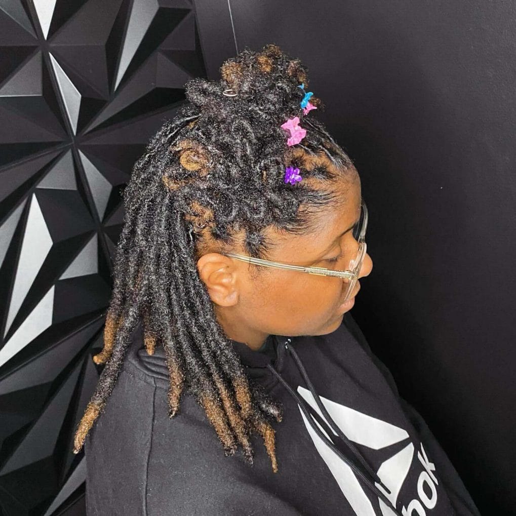 Medium-length dreadlocks styled half-up with colorful clips for school
