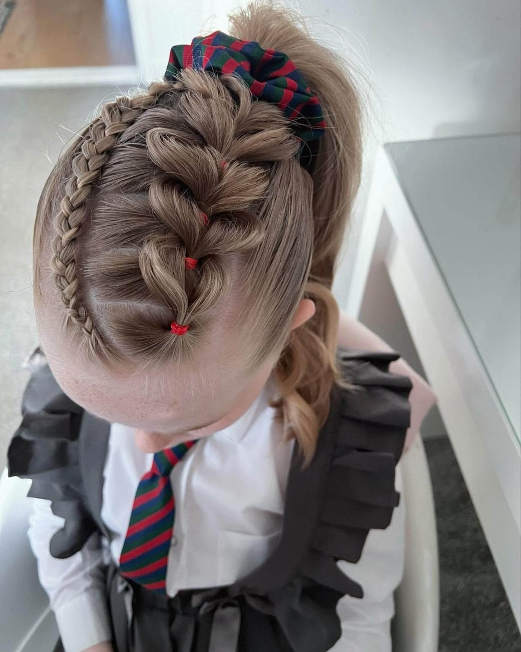 Intricate braids leading to a high ponytail with colorful elastics for school