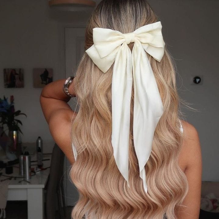 Sun-kissed wavy locks with big cream bow for beach days