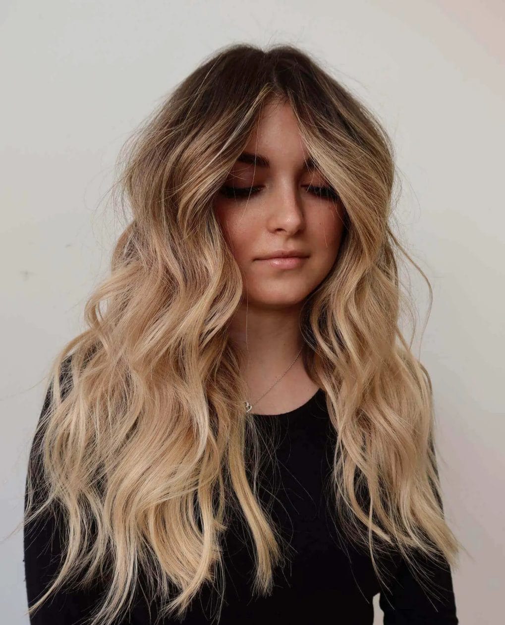 Long balayage waves from dark to beach blonde with airy bangs