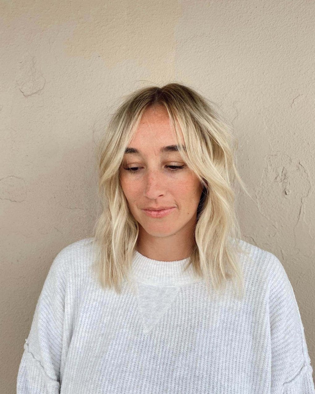 Beachy waves lob with blonde balayage and refined curtain bangs.