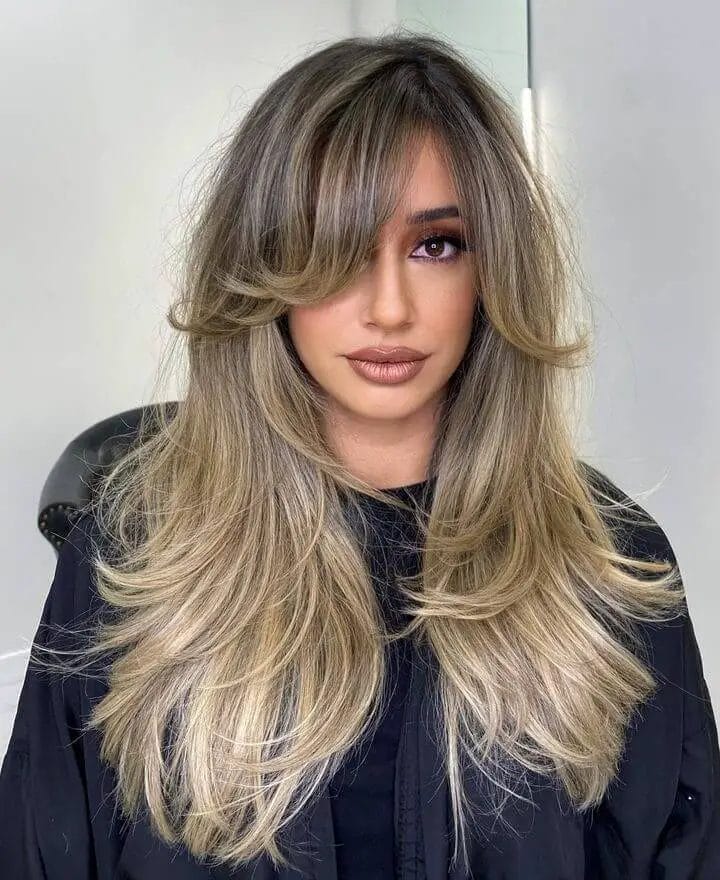 Layered hair in beige tones inspired by 90s bombshell style.
