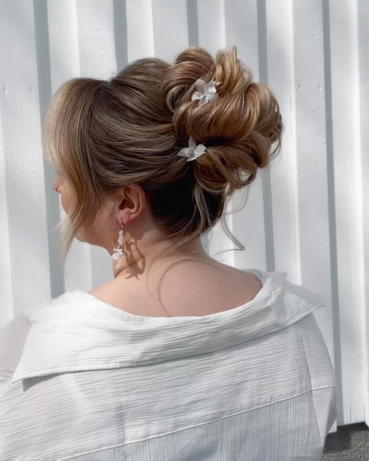 Blonde high bun with layers, loops, and white flowers