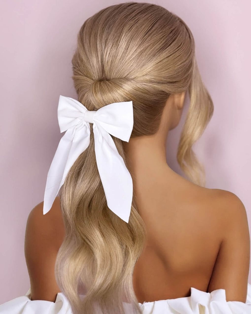 Blonde balayage with elegant twist and white bow for summer glamour