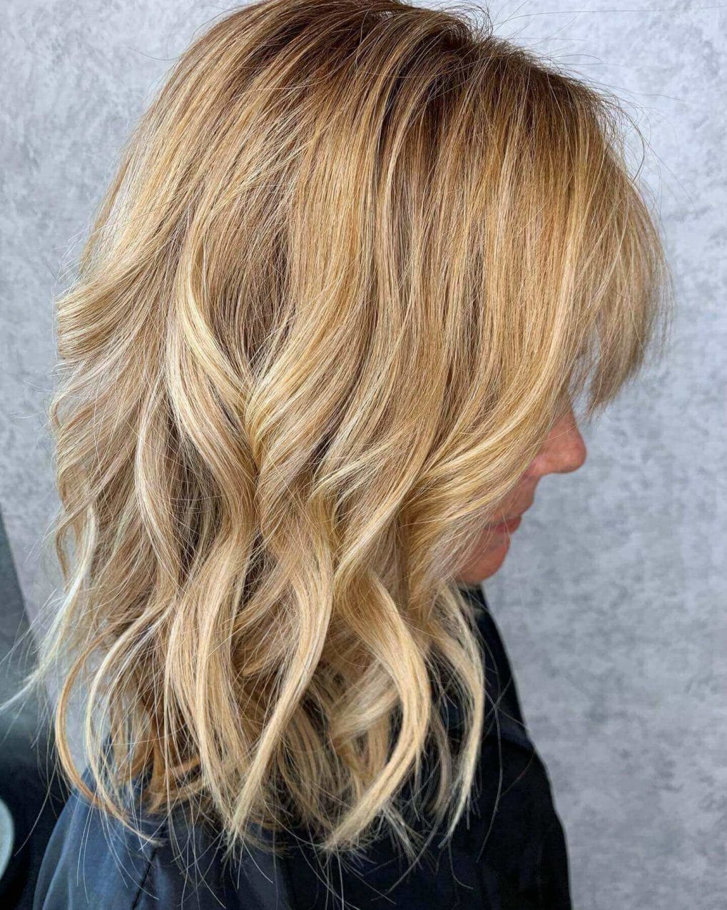 Sun-kissed blonde, medium-length hair with playful waves and perfect layers.