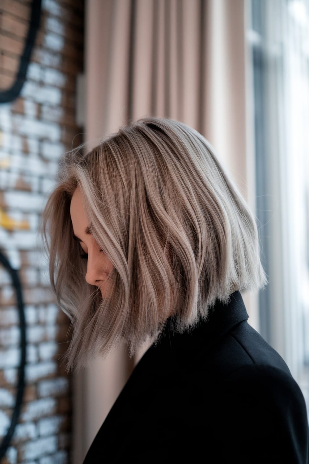 A side profile of a woman with a blunt cut hairstyle and subtle highlights.