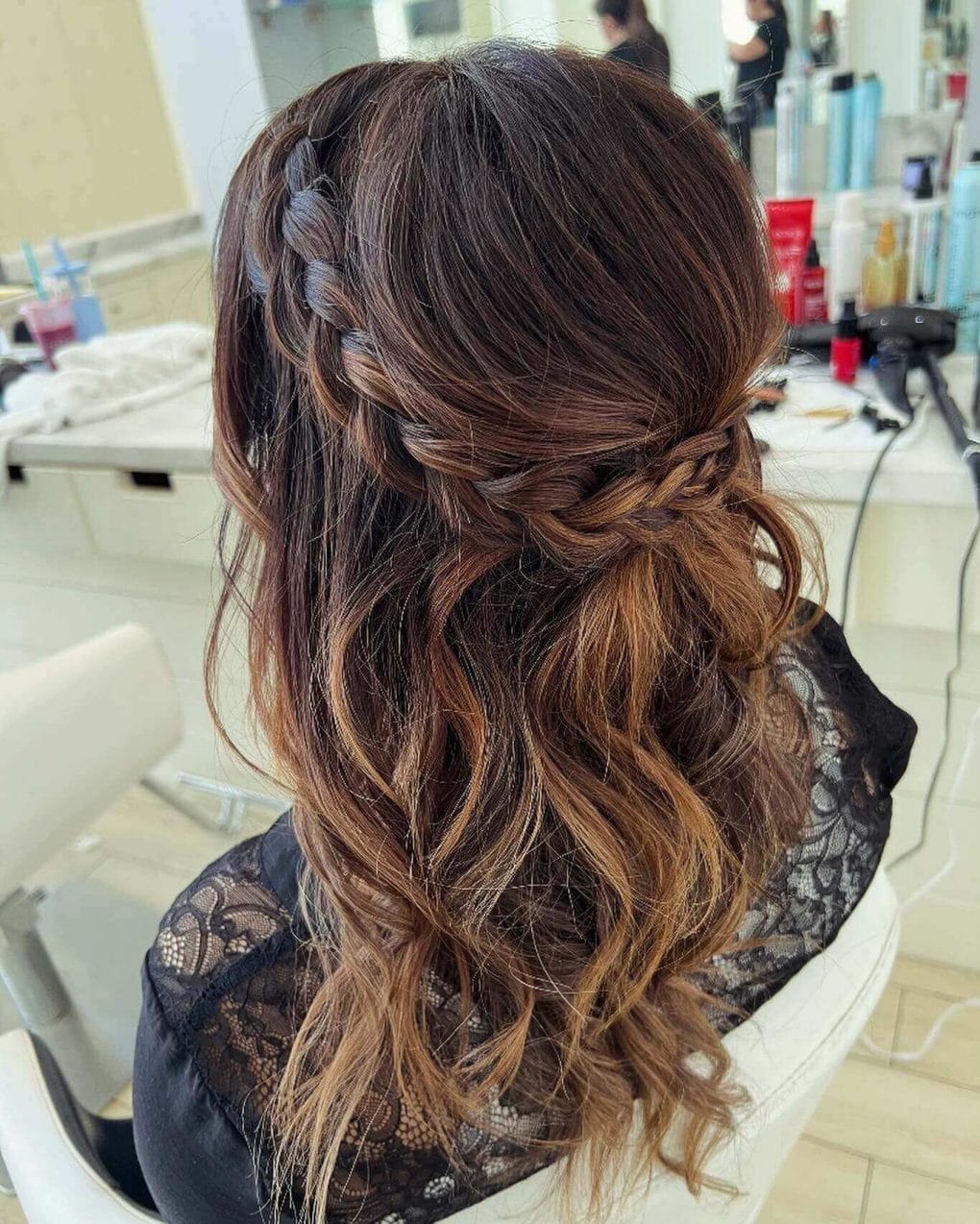 Elegant boho side braid flows into wavy, caramel-highlighted hair