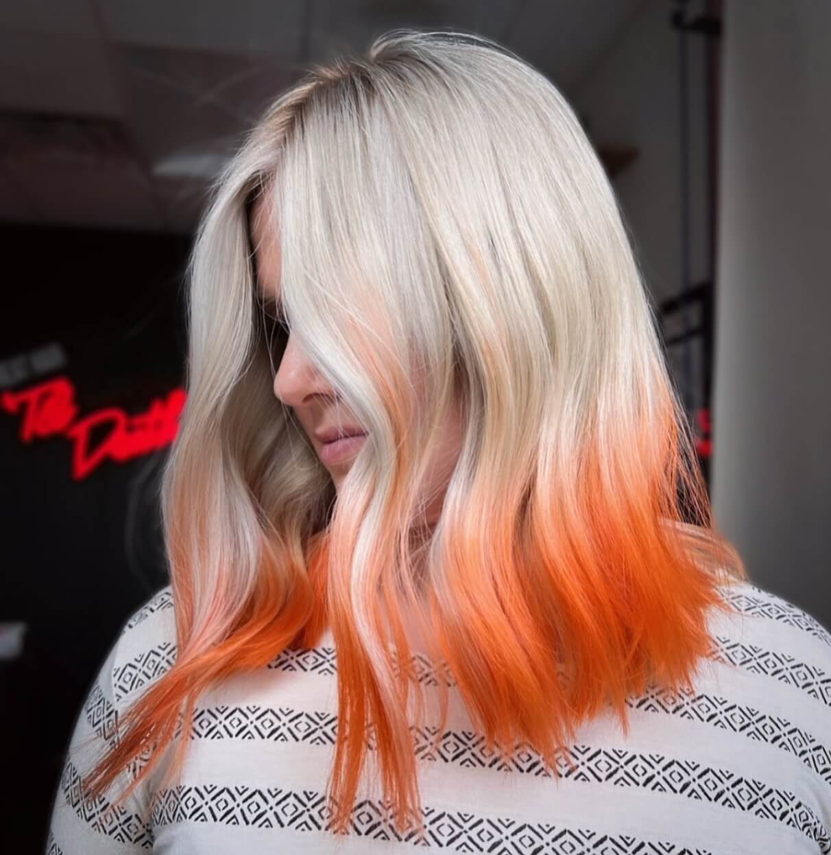 Bold blonde bob with orange tips and chic side part