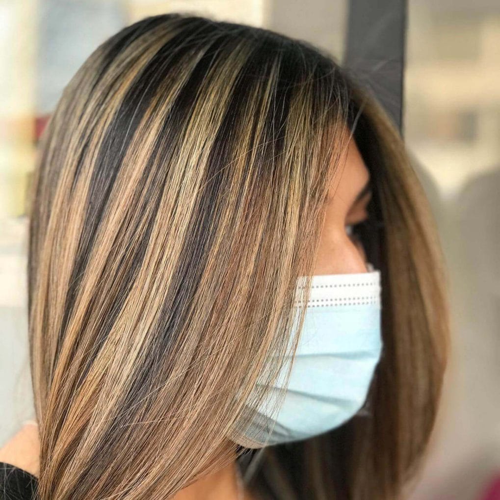 Bold blonde streaks on dark brown, sleek and straight haircut with layered look.