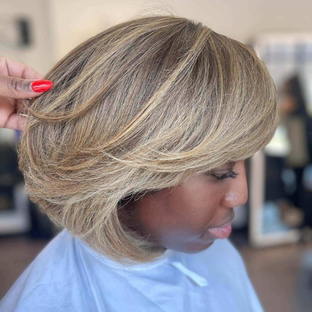 Short bouncy bob silk press in light blonde with playful layers and dark roots