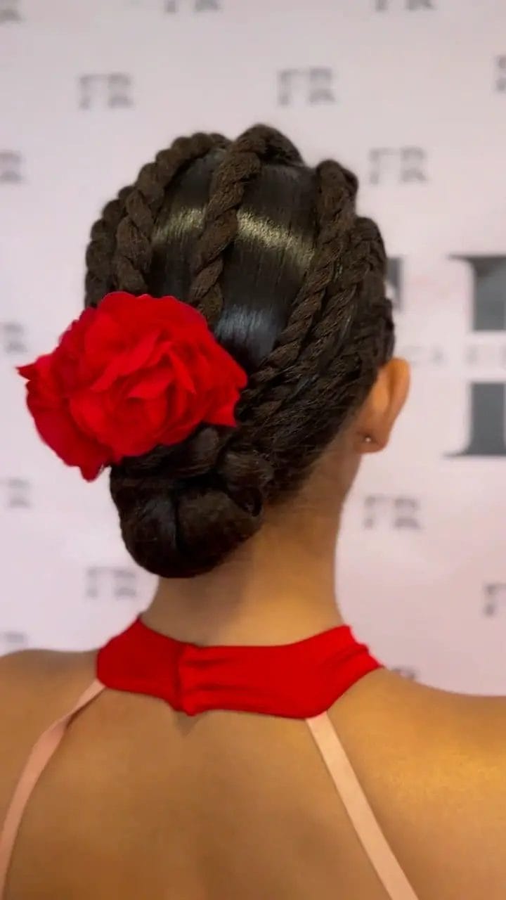 Glossy braided bun with a vibrant red flower accent