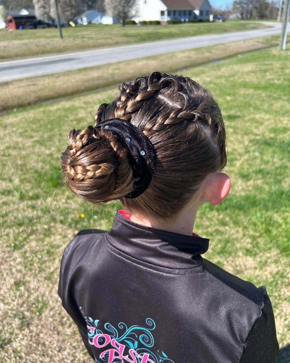 Functional gymnastics bun wrapped in a braid and adorned with a sparkling black band for a decorative touch
