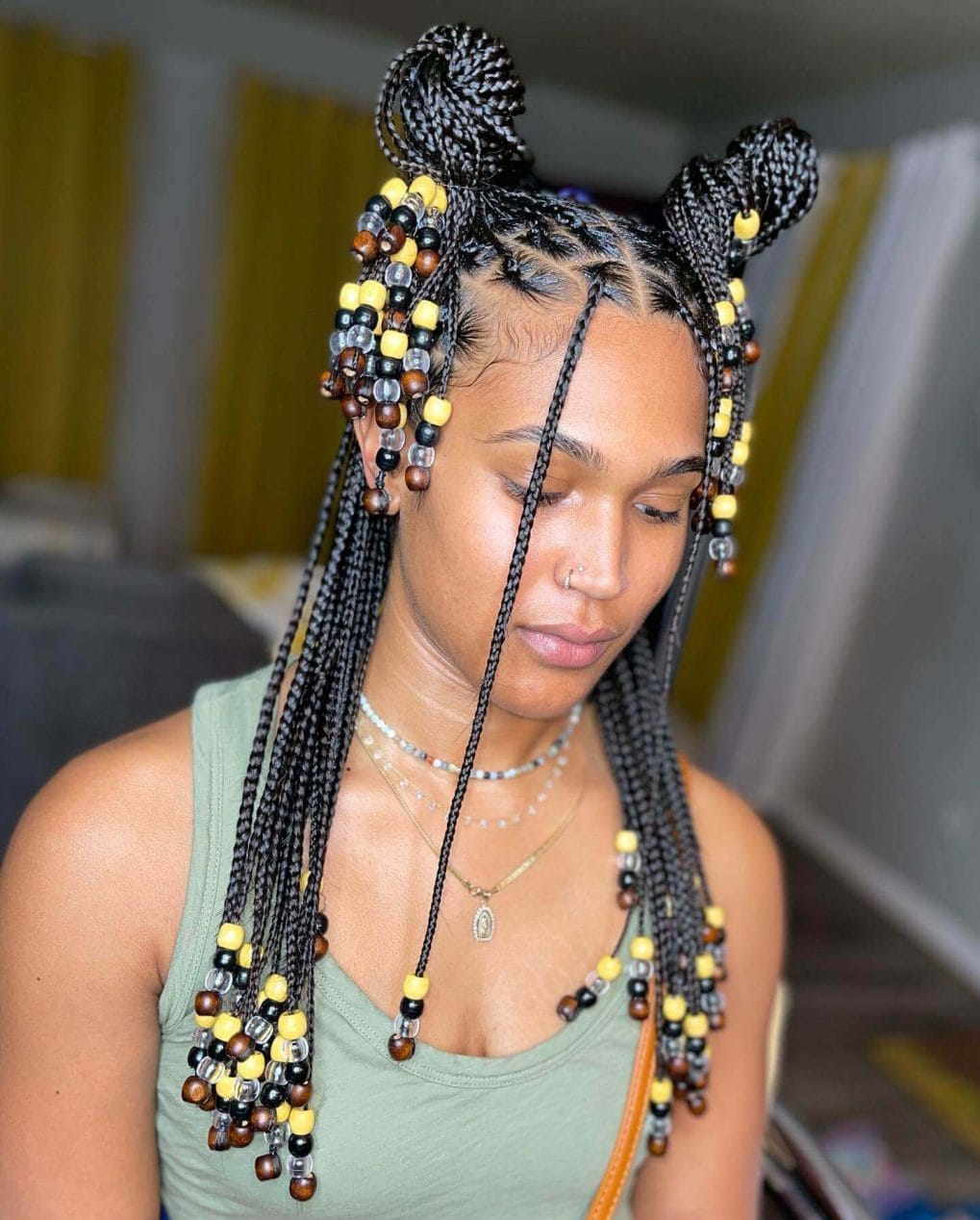 Tightly woven braids in playful buns with black, yellow, and earth-toned beads.