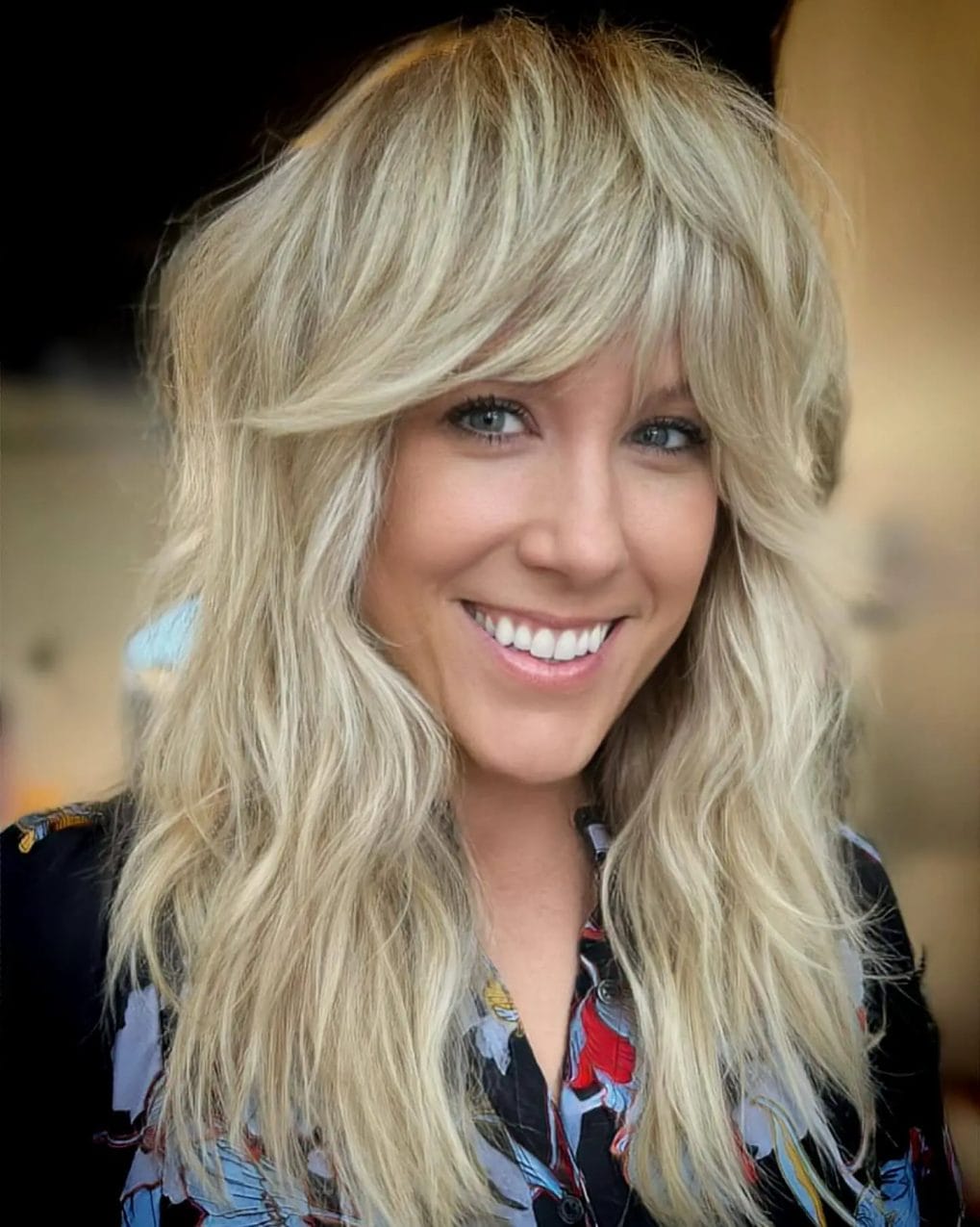 Bright blonde shaggy mullet with long wavy layers and a sunny, feathered fringe