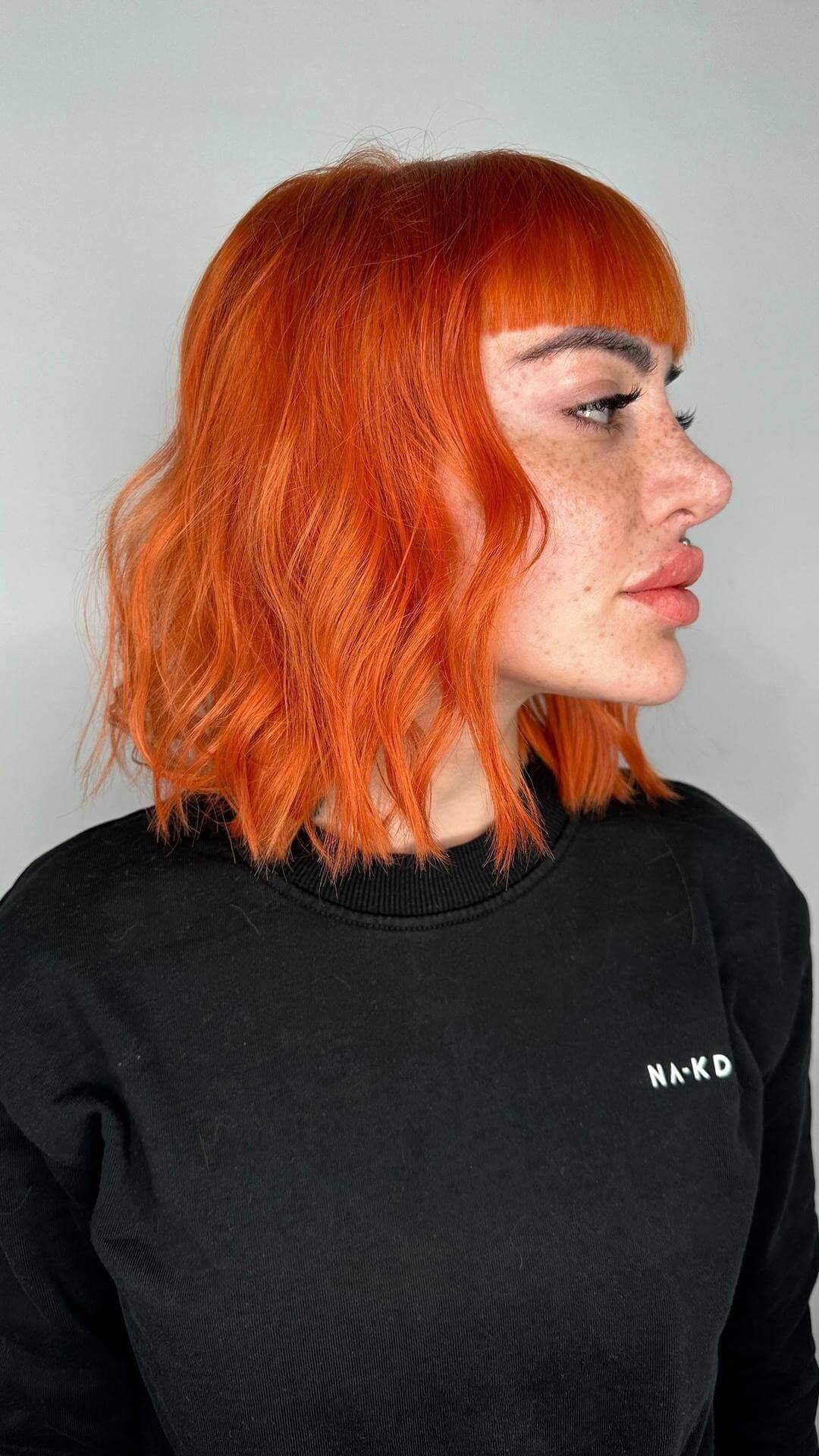 Bold bright orange shaggy bob with straight fringe and lively layers