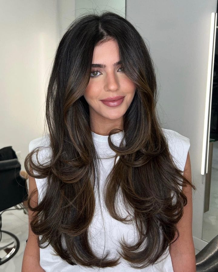 Radiant brunette balayage with 90s bombshell layers giving depth and movement.