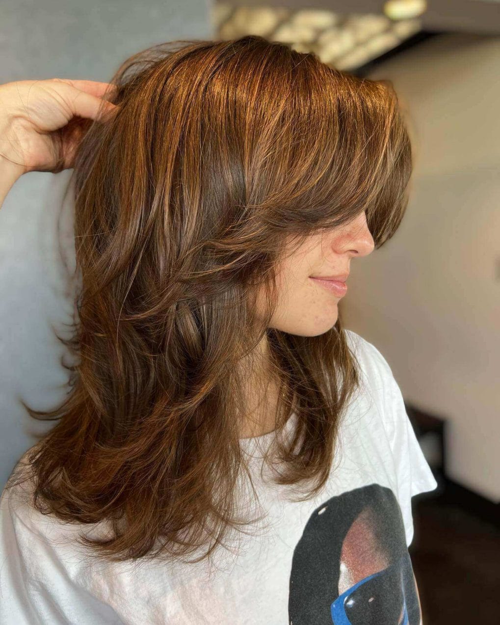 Brunette woman with curtain bangs and short butterfly haircut.