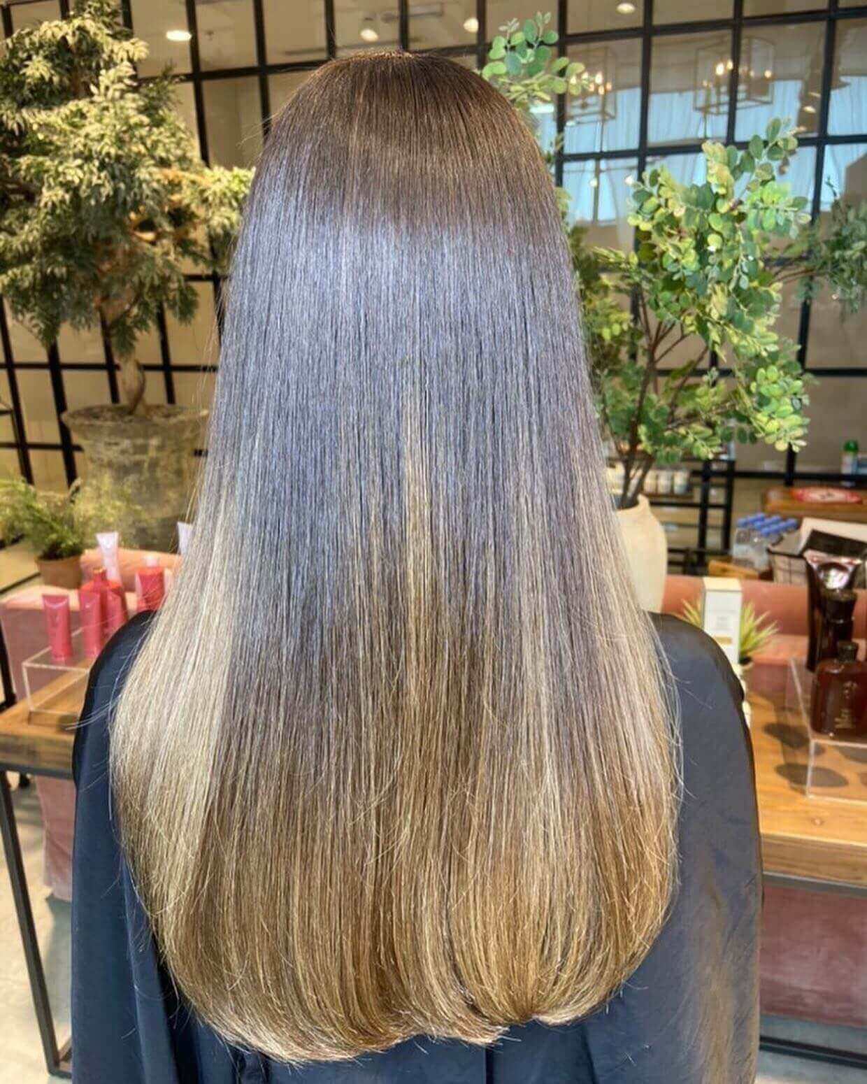 Straight hair with dark brunette roots and warm honey blonde tips balayage.