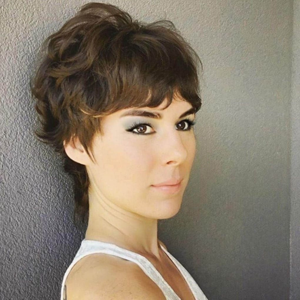 Brunette mullet wavy pixie with a stylish front fringe.