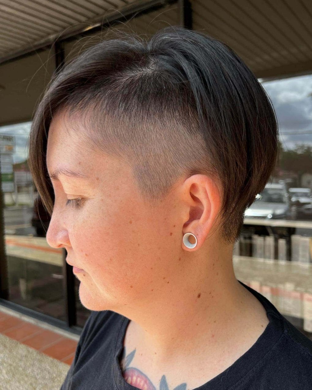 Modern brunette pixie cut blending into a subtle undercut with textured layers on top.
