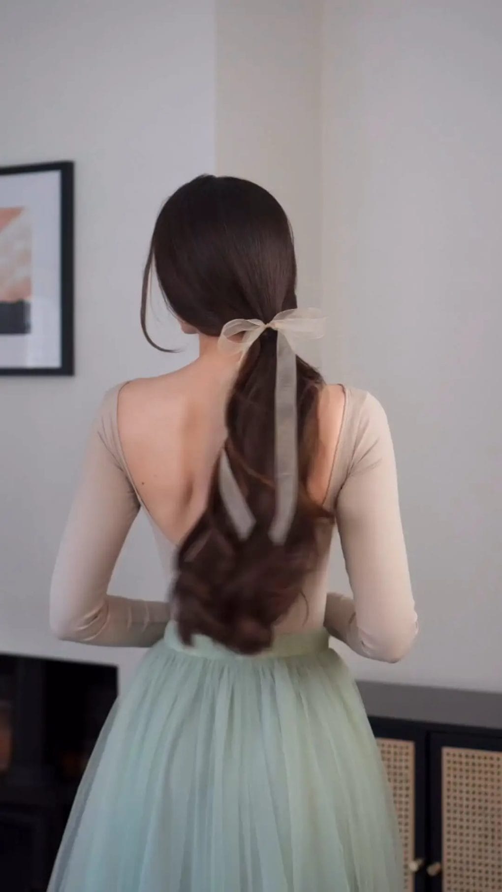 Luxurious long brunette ponytail tied with a sheer ribbon, softly waved