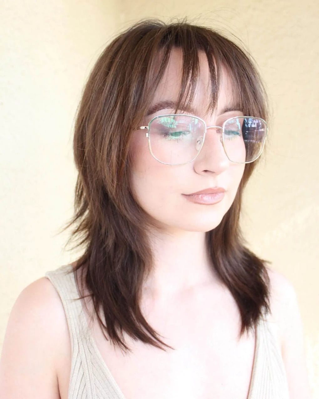 Shoulder-length brunette with see-through bangs and oversized glasses.