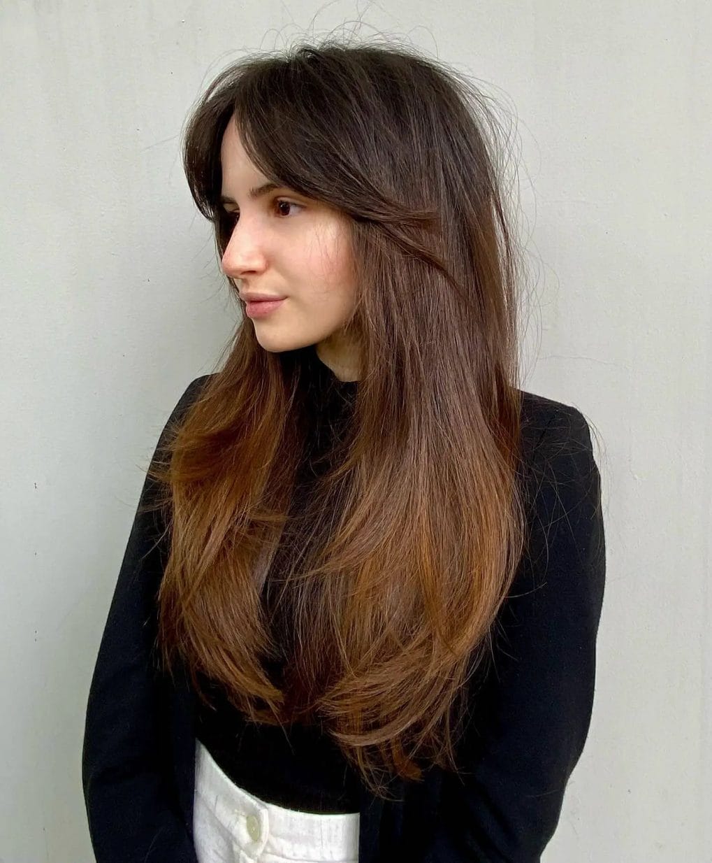 Deep brunette cascading into auburn with delicate feathered bangs, showcasing a soft, romantic look.