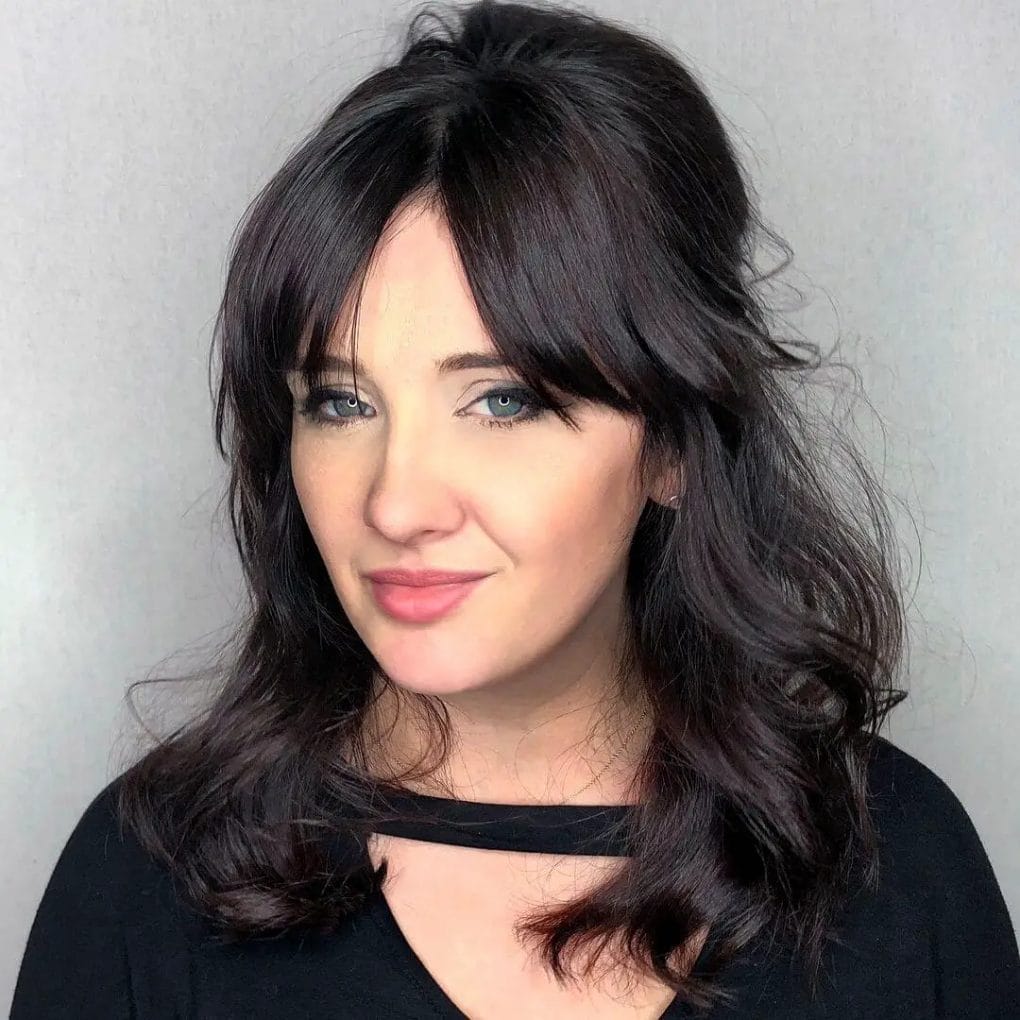 Rich brunette waves with a face-framing curtain fringe, showcasing natural flow and movement.