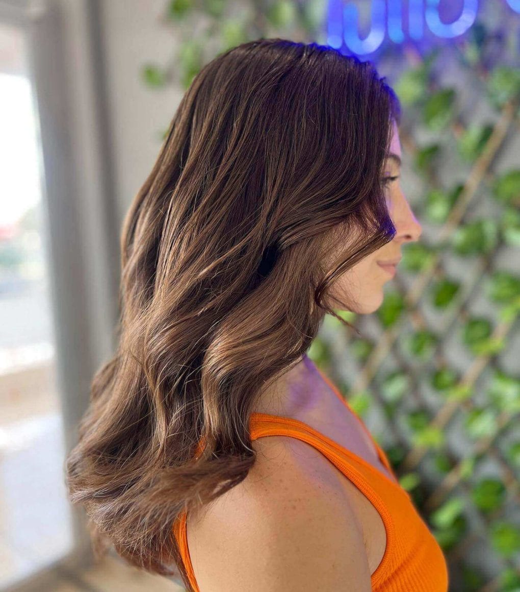 Wavy brunette short butterfly haircut capturing light and shadow.