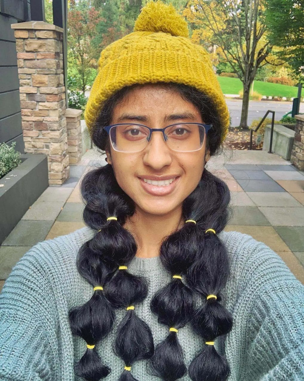 Playful bubble braids paired with a vibrant mustard beanie for a bold look.