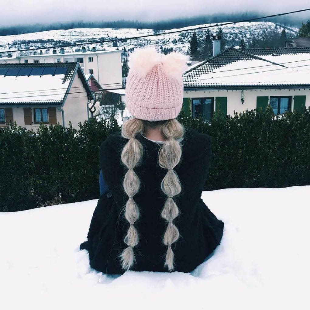 Spirited bubble braids contrasted by a pastel pink beanie with fluffy pompom.