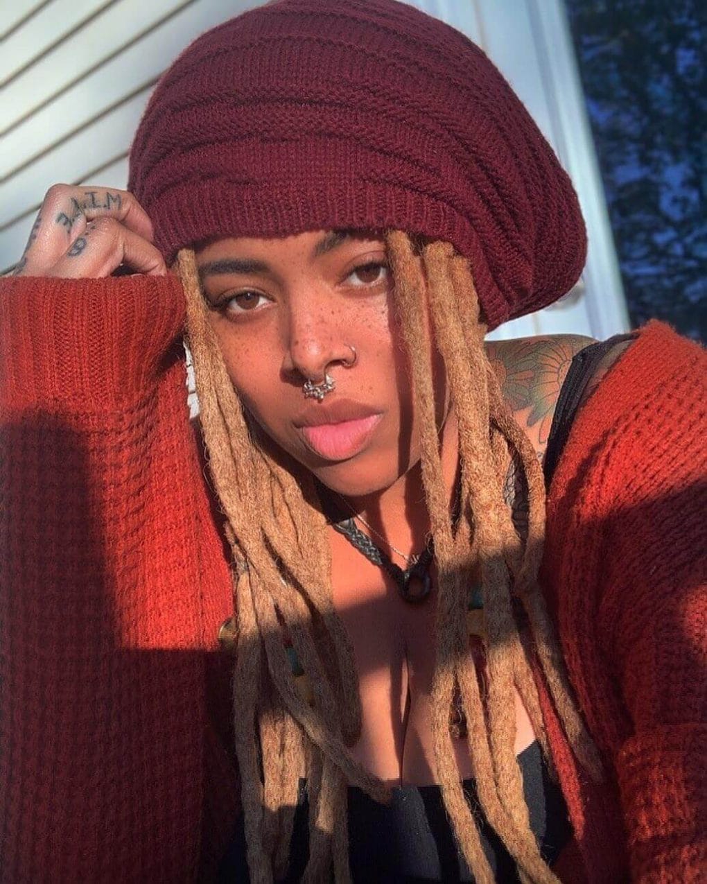 Effortlessly cool dreadlocks peeking from under a burgundy beanie.