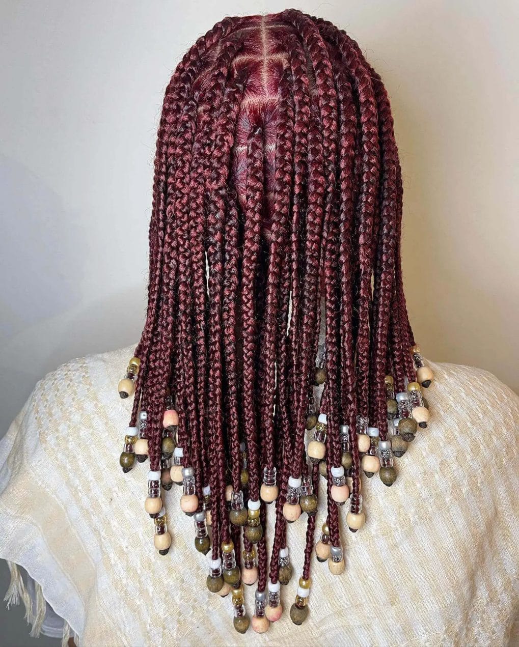 Sleek burgundy braids with muted earth tone beads in varying shapes.
