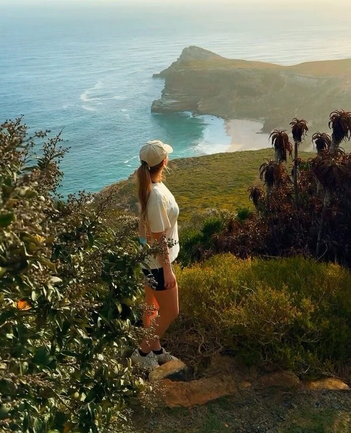 Seafront hiker with ponytail flowing from under cap in breezy setting