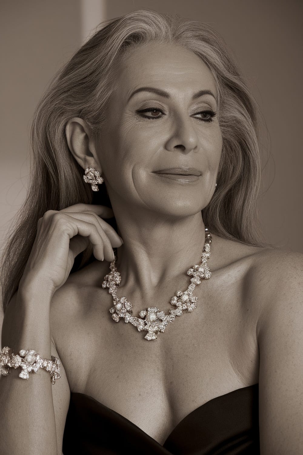 A woman with long hair styled elegantly, adorned with a floral statement necklace and matching earrings.