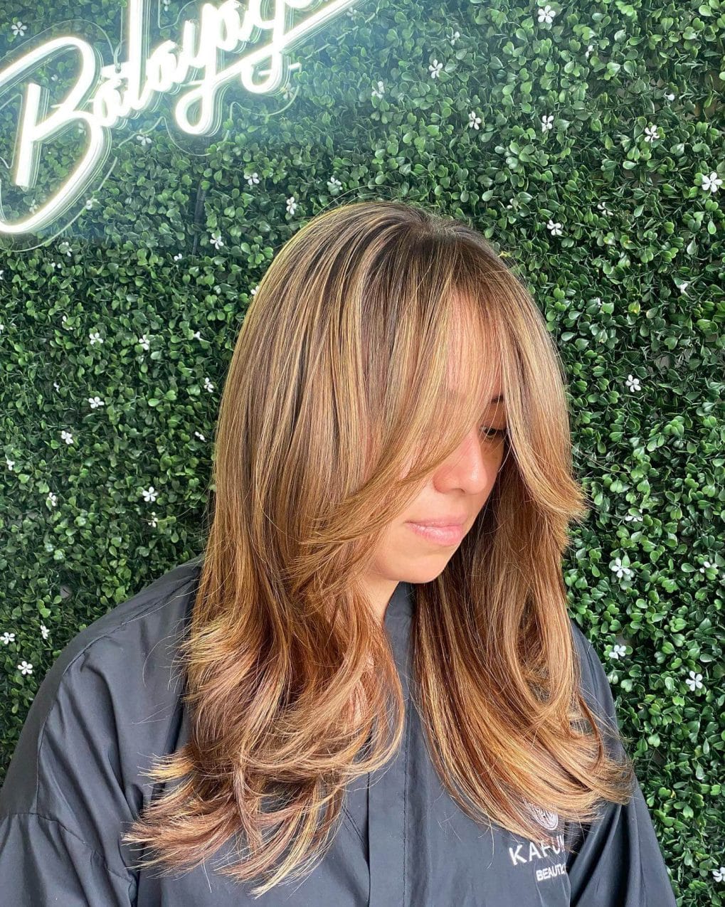 Caramel balayage Butterfly Cut complemented with soft curtain bangs.