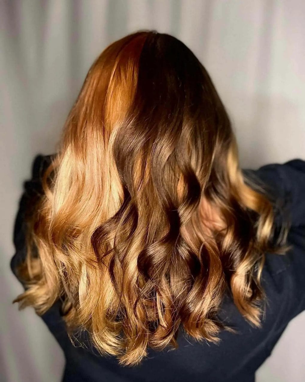 Warm caramel fades into dark chocolate roots in curly style