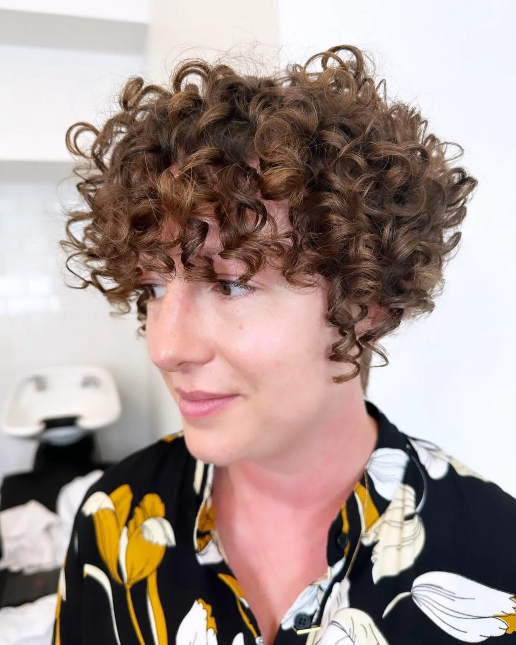 Warm chestnut bouncy curls framing the face in playful pixie