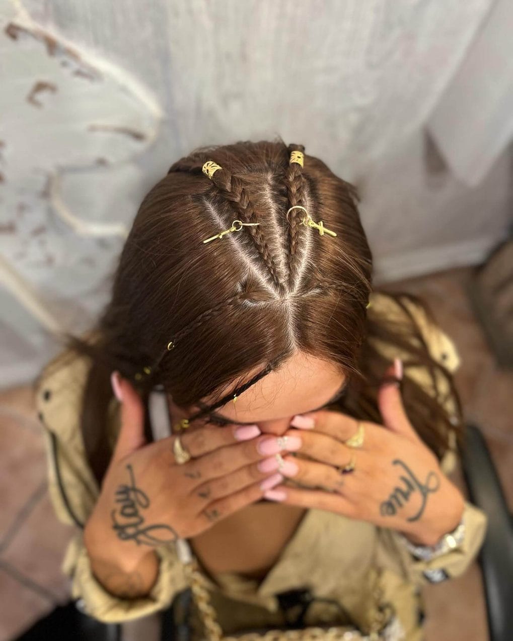 Chestnut-brown cornrow braids adorned with small gold beads and cuffs.