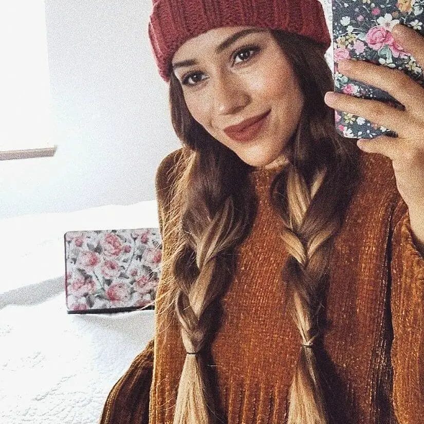 Relaxed fishtail braids in chestnut hues beneath a ribbed burgundy beanie.
