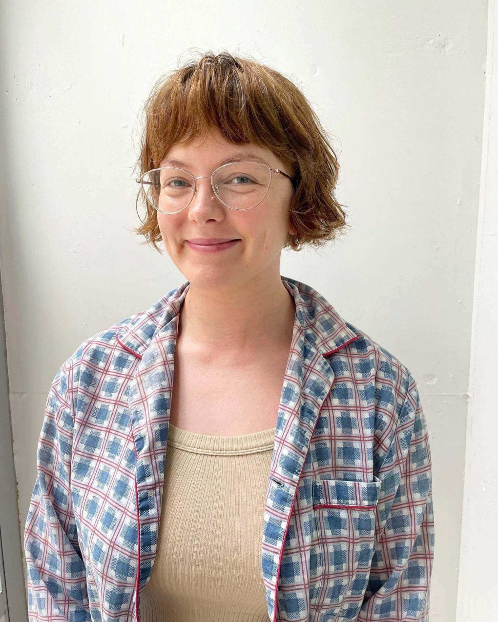 Tousled chestnut short hair with textured bangs and quirky round glasses.